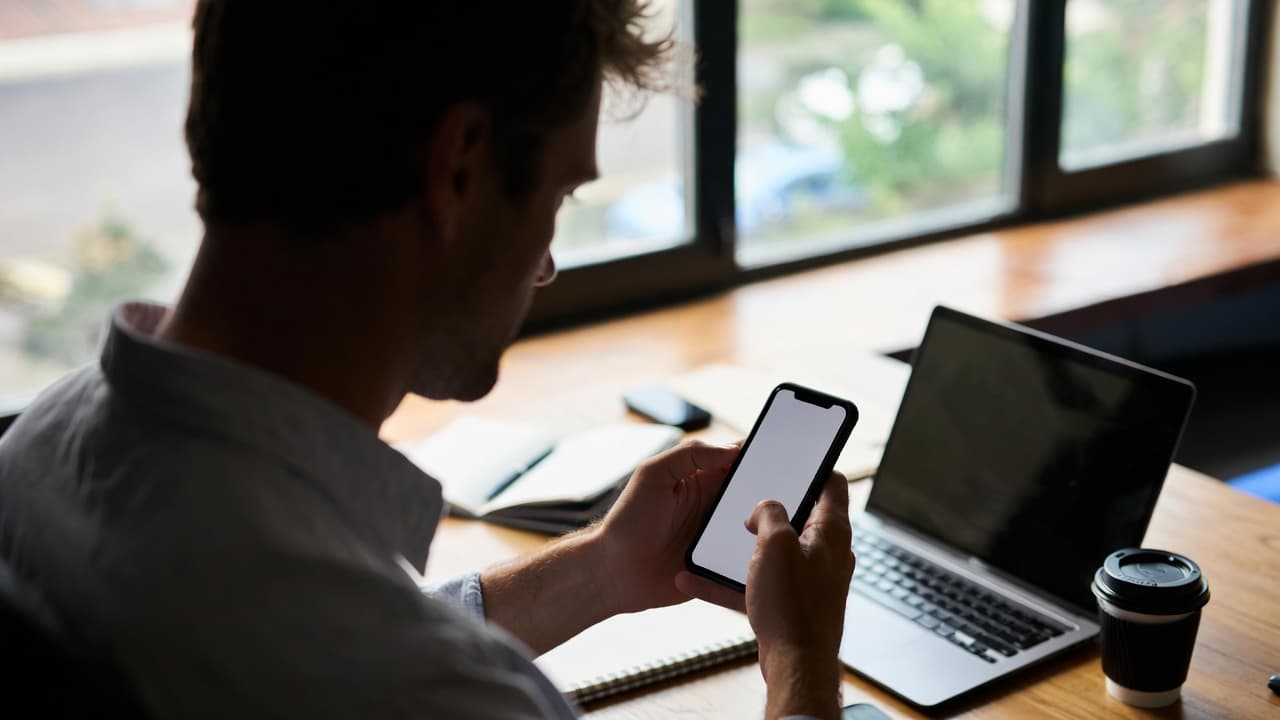 Smartphone mit Zeiterfassungs-App in einem hellen Arbeitsumfeld