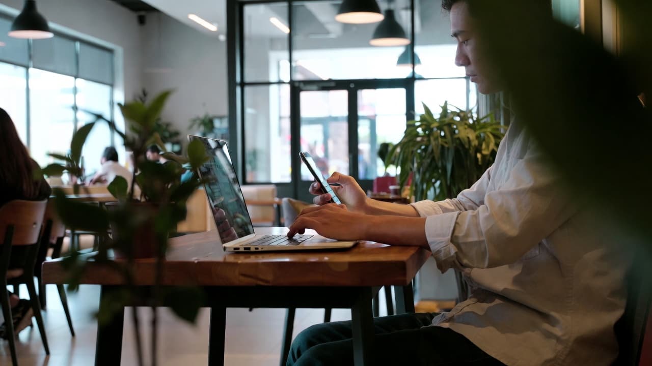 Freelancer erfasst Arbeitszeit mobil per Smartphone in einem Café