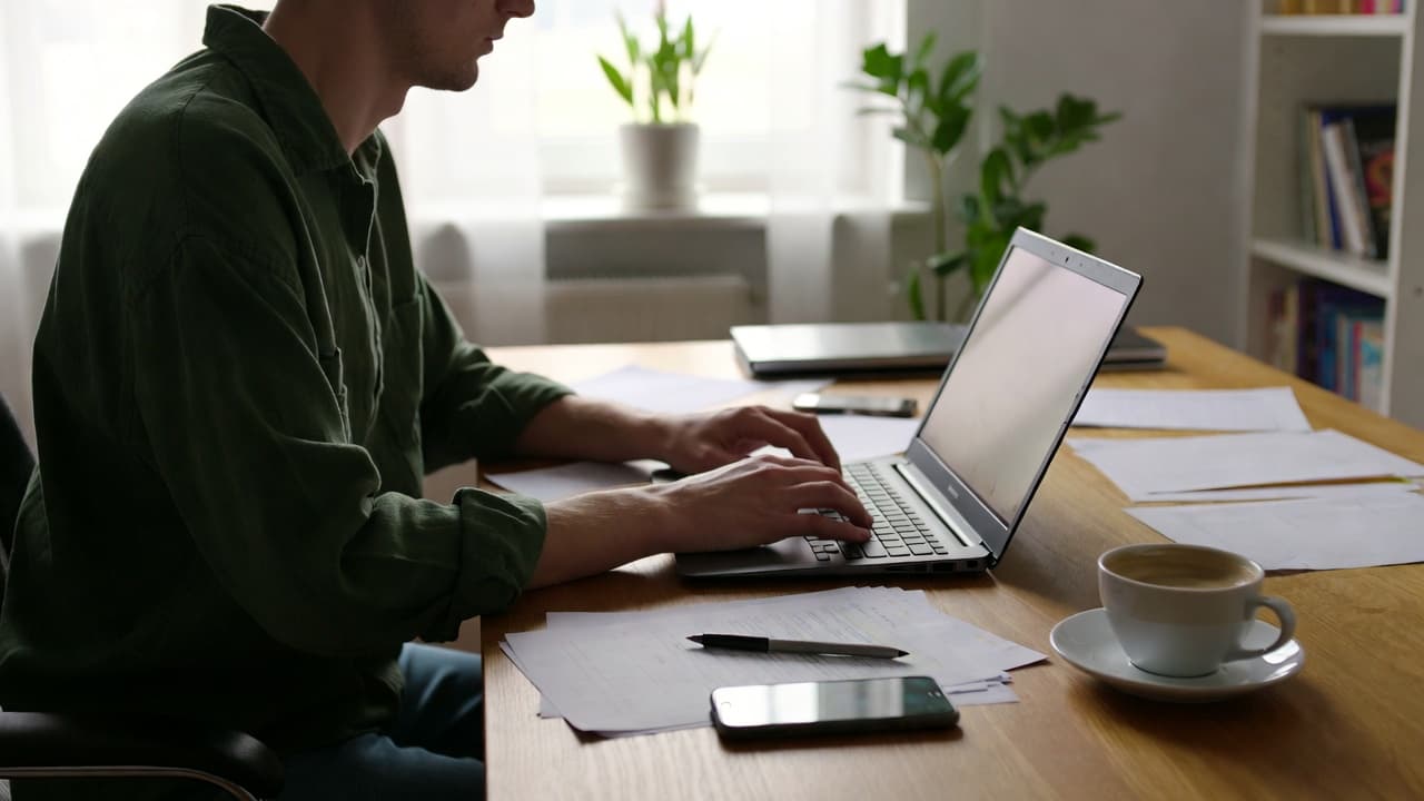 Freelancer am Schreibtisch mit Laptop bei der Zeiterfassung