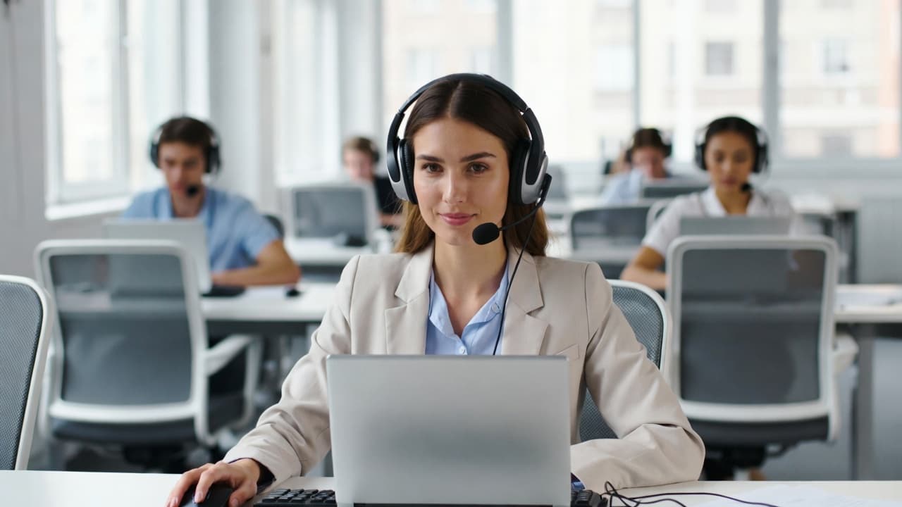 Call-Center-Mitarbeiter mit Headset bei der Zeiterfassung am Laptop